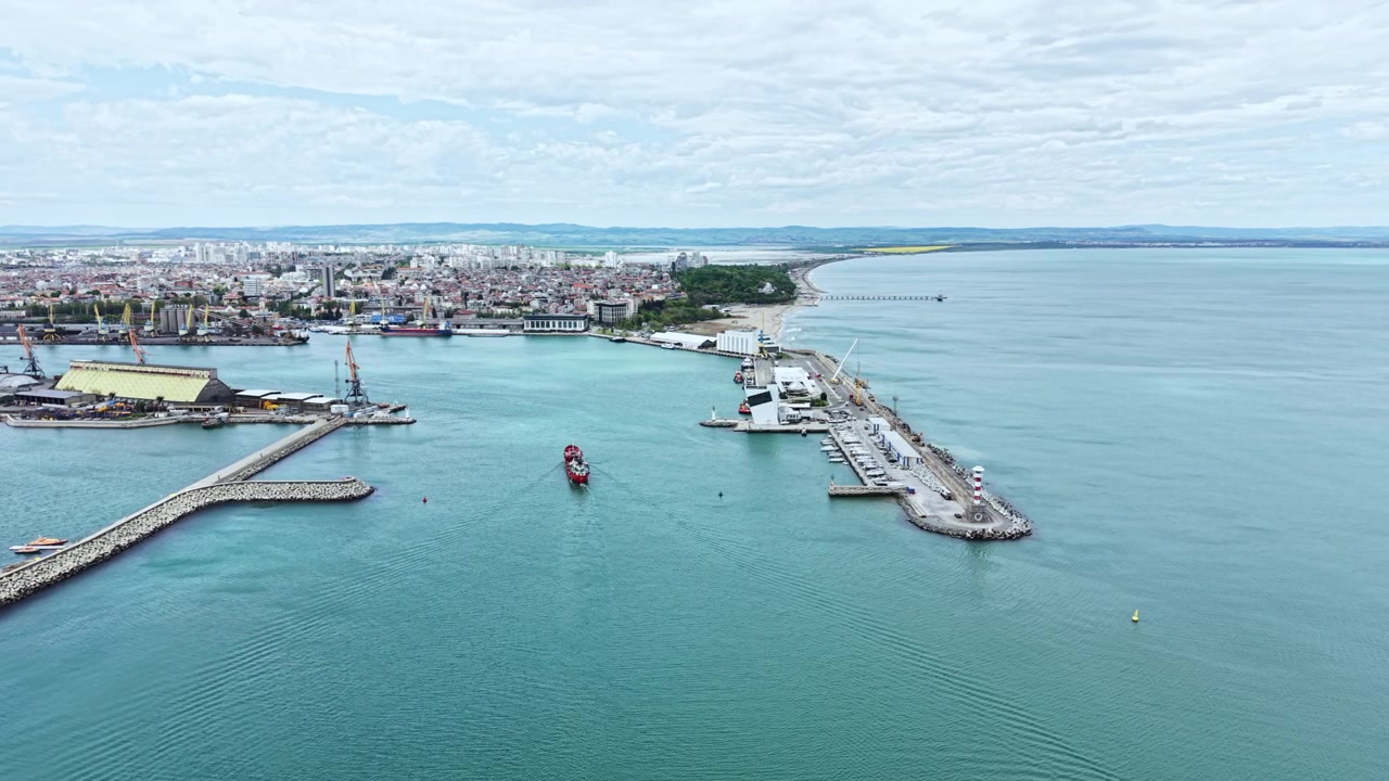 Um barco navega pela água perto de uma cidade costeira com docas e uma marina em um dia claro