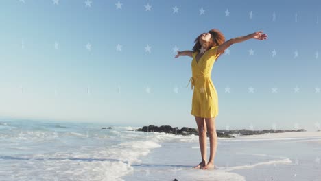 animación de estrellas sobre mujer afroamericana levantando las manos en la playa