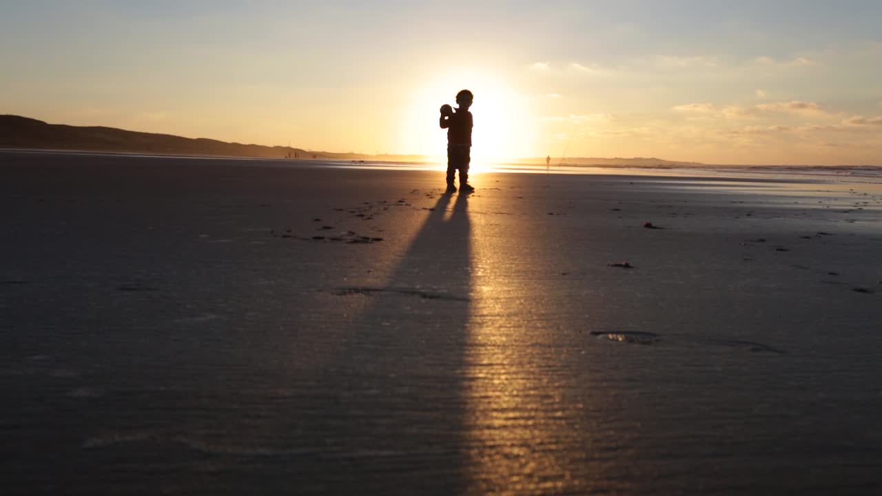 해질녘 해변에서 축구를 하는 아이