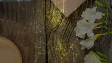 flower cluster being 3d rendered on wooden table showing coffee, notebook, glowing golden particles