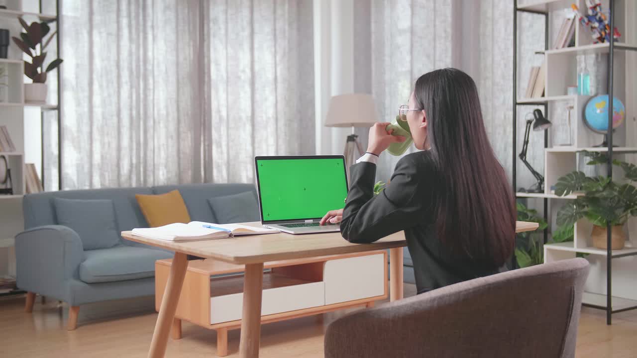 노트북과 녹색 화면으로 집에서 일하는 여성