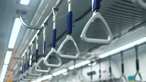 hanging alley of public transportation, bus or train interior. medium shot of handles hanging on moving train