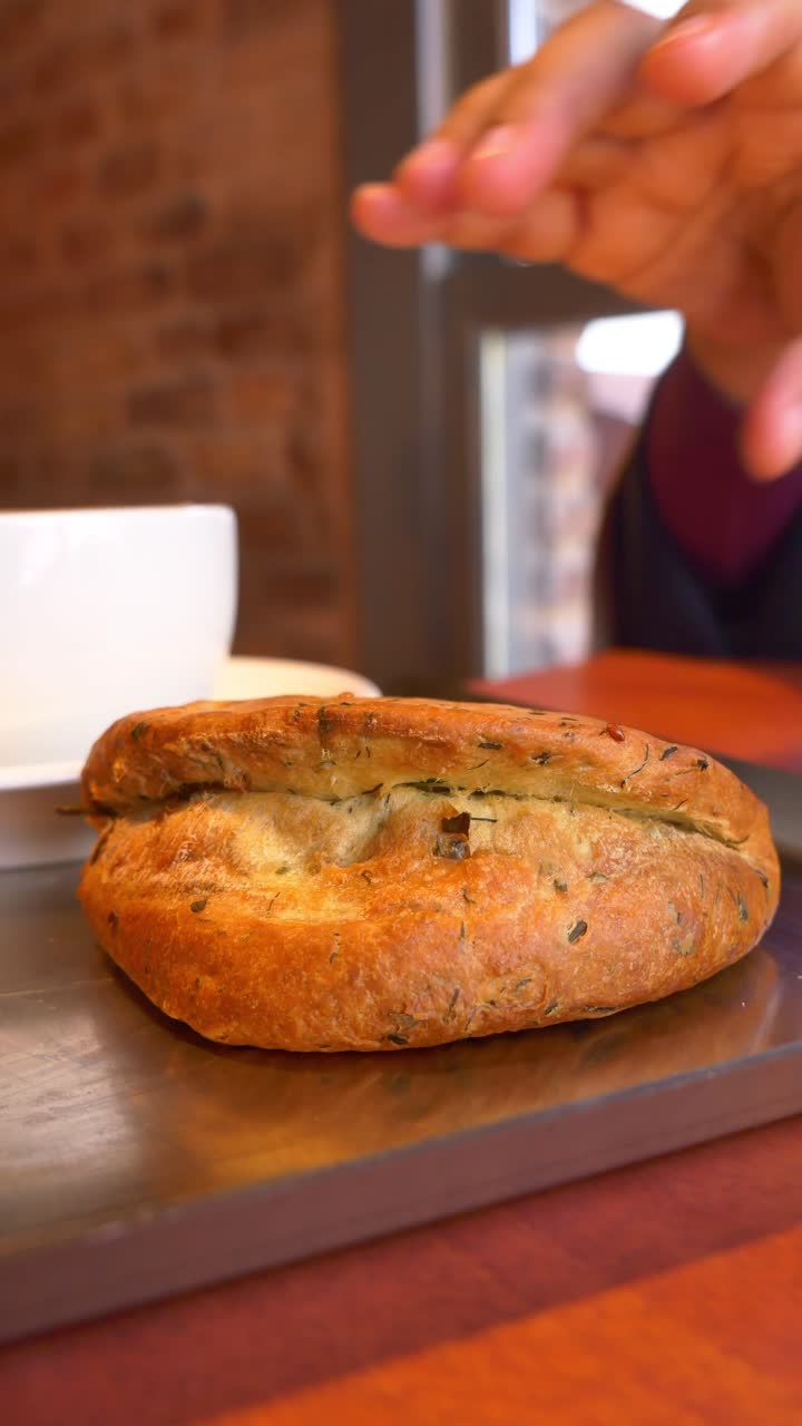 Mano che prende una pagnotta di pane appena sfornata da un vassoio.