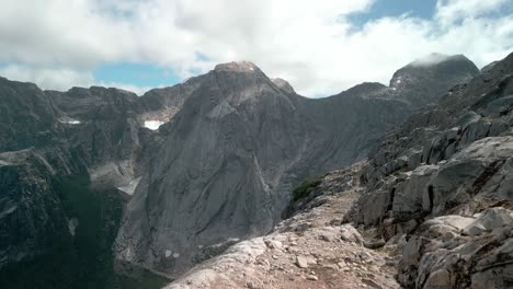 caminante que se acerca a la cámara mientras el dron pasa y te permite ver un valle remoto
