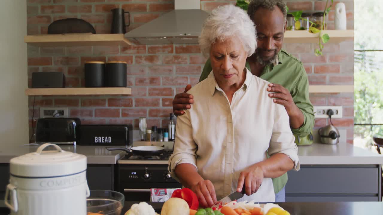 Senior African American husband and mixed race wife cooking together at home