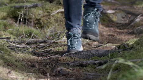 Slow-motion-of-a-person-walking-carefully-with-hiking-shoes-on-forest-pathway-in-the-forest