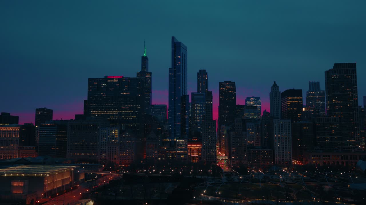 Emotionally charged aerial of Chicago at dusk, vivid pink and purple sky frames the city's towering skyline, evoking ambition, aspiration, and the allure of urban life