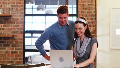 Businesswoman-interacting-with-coworker-while-working-on-laptop