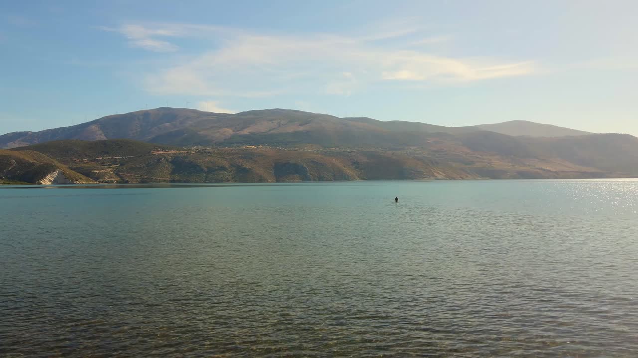 человек, идущий по мелководью ионического моря