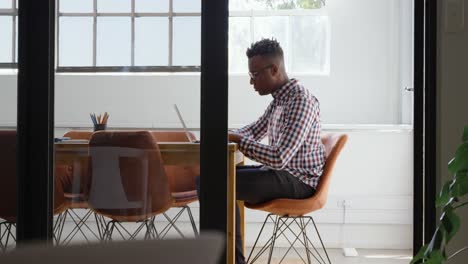 Side-view-of-young-black-businessman-working-and-siting-in-conference-room-of-modern-office-4k