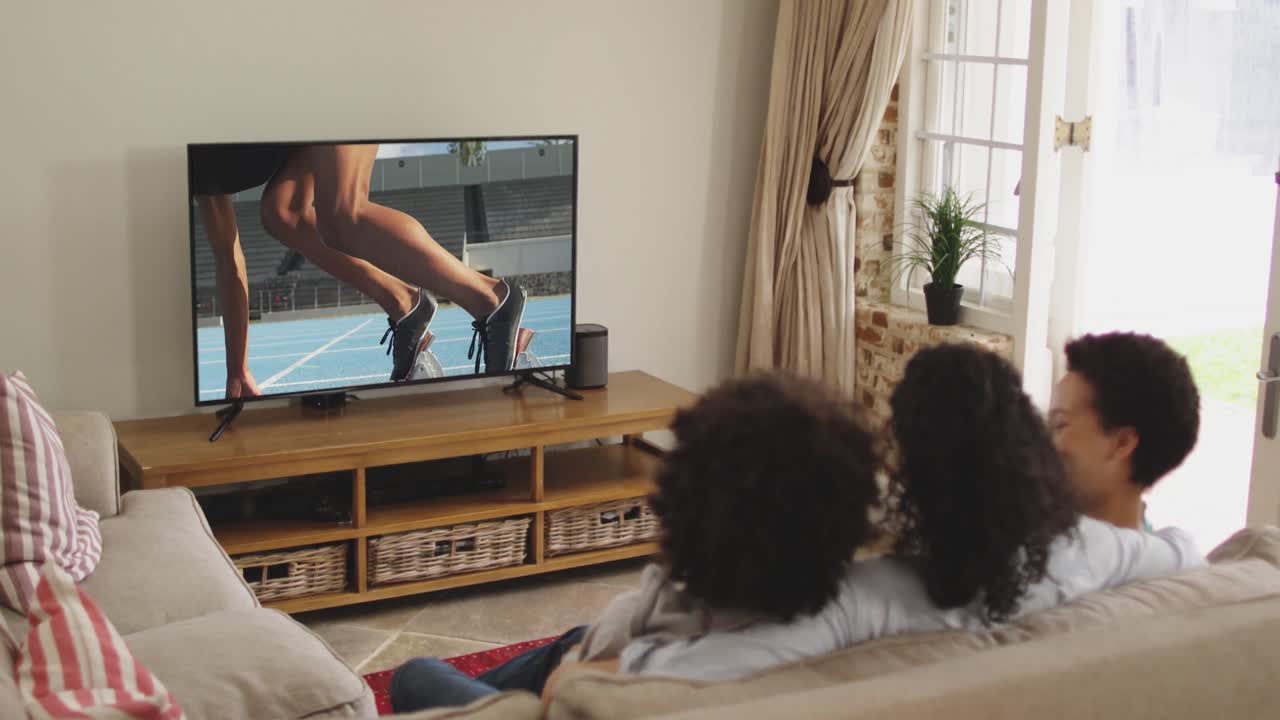 Composizione di famiglia felice seduta insieme a casa che guarda un evento di atletica leggera di corsa in TV.