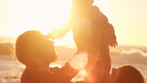 father and mother playing with their baby boy in the beach 4k