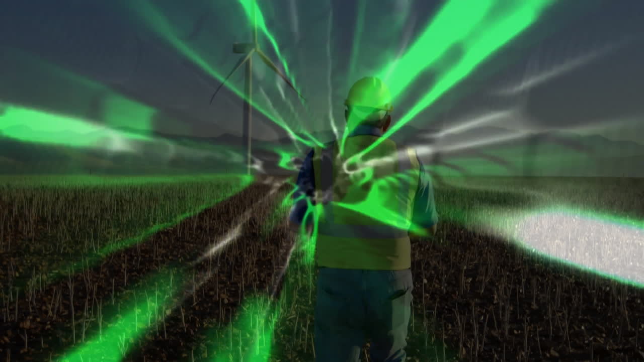 Engineer wearing vest monitoring wind turbine using smartphone with green energy waves pulsing