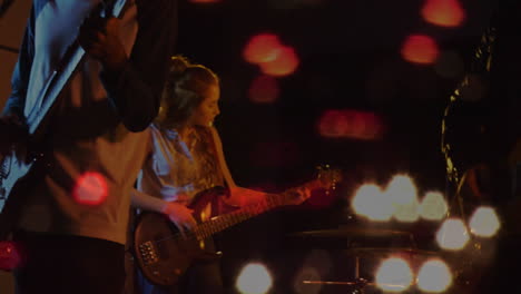 bandmates playing electric guitar and bass on dim music stage, overlaying animated soundwave icons