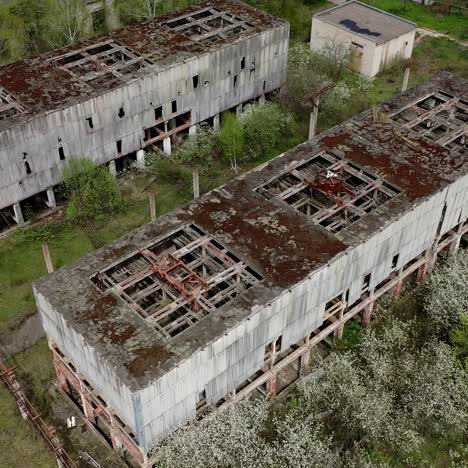 destroyed factory buildings with holes in roofs. old abandoned industrial plant. ruined manufacturing on green nature background. view from above