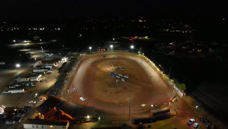 aerial flyover of oval dirt track racing during a race at night