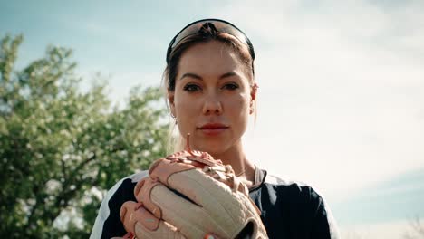 a dramatic close up of a female softball athlete posing with her baseball glove on a practice field