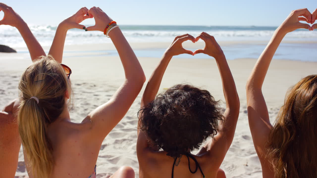 amigos haciendo formas de corazón en la playa