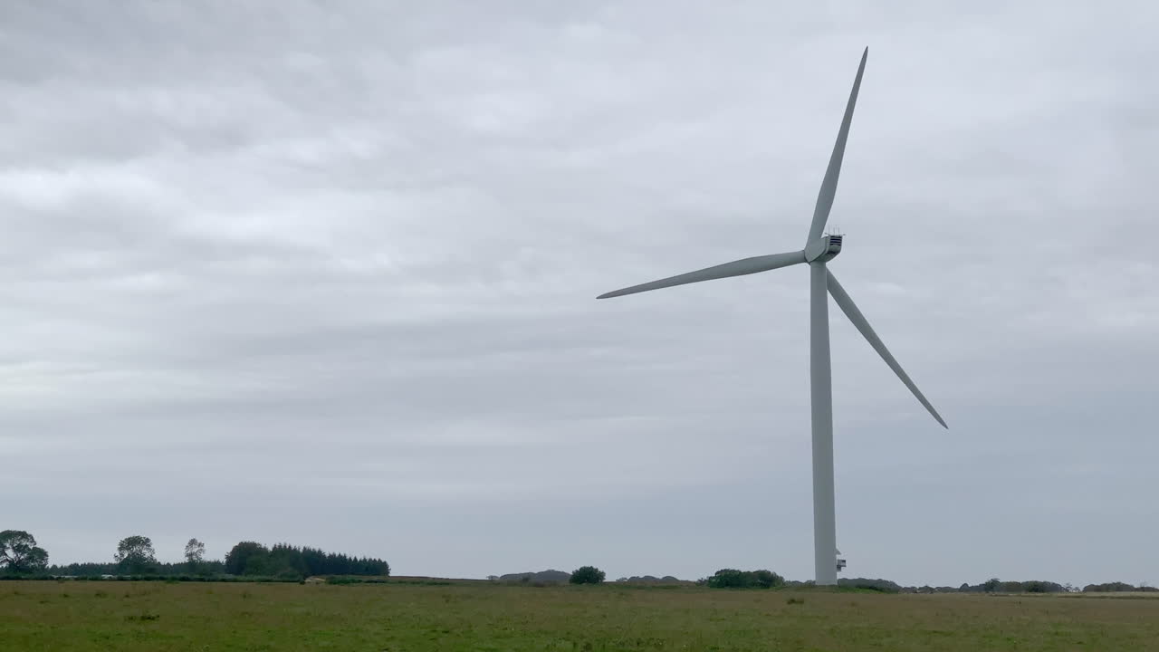 задний снимок одиночной ветряной турбины, вращающейся на ветряной электростанции в нортумберленде в пасмурный день