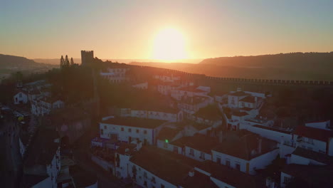 sundown lighting suburb rooftops and ancient wall drone. silhouette of castle