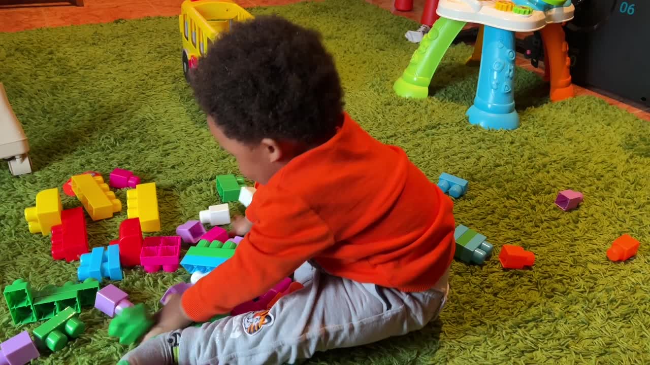 Exotic two year old african european child playing at home with color plastic blocks happy and funnny