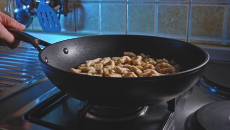 tossing chicken breast pieces cooking in a pan