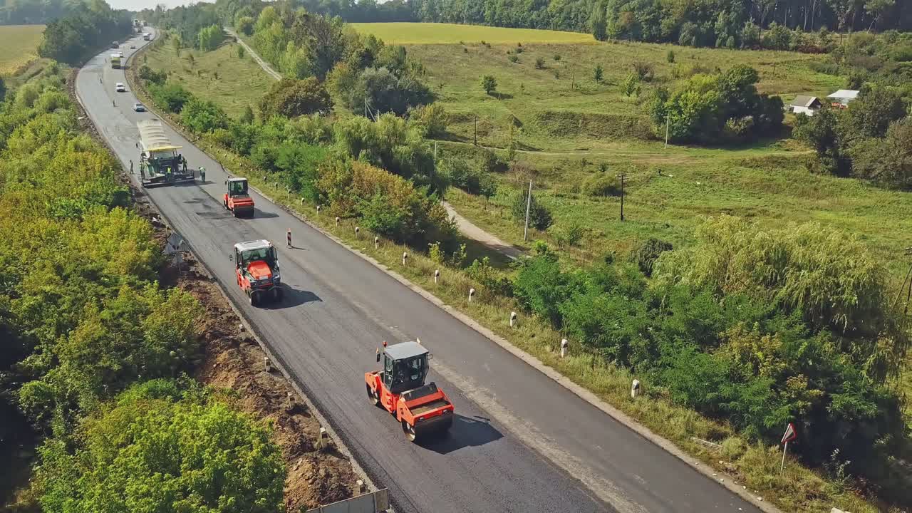 Aerial view on the road rollers working on the new road construction site. Road construction works.