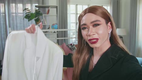 young transgender woman fashion blogger holding camera and showing cloth for sell online, selfie