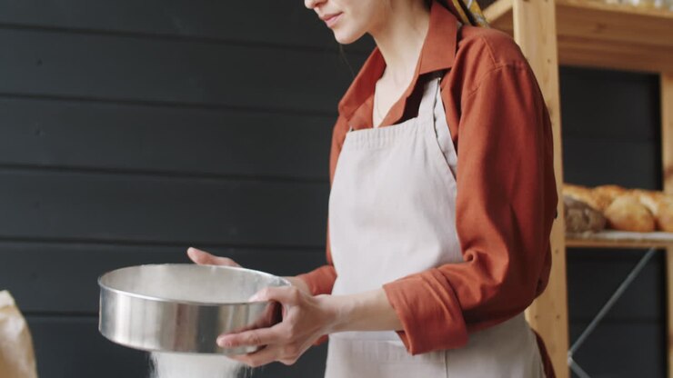 Beautiful Female Baker Sifting Flour in Kitchen