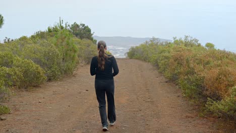 atractiva mujer corredora en las montañas de tenerife, vista de atrás