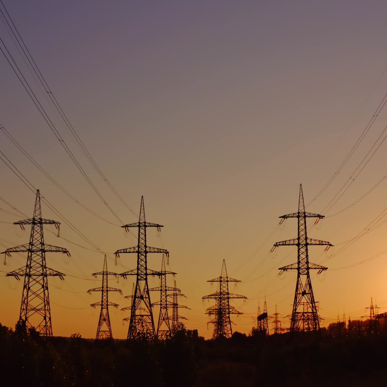 Silhouette of high-voltage towers. Electricity pylons on energy station on the background of beautiful sky at sunset. Electricity station and high-voltage power lines.View from below.