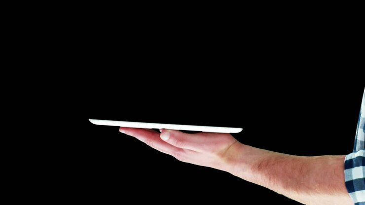 Mano destra sospesa, che tocca, stringe, ruota mentre la mano sinistra tiene un tablet bianco regolando l'HUD