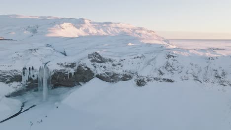 aerial panoramic view of a winter landscape covered in snow, over seljalandsfoss waterfall, in iceland, at dusk