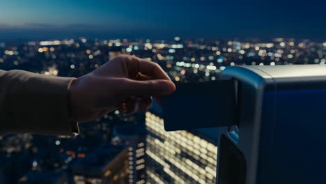 a hand inserting an access card into a reader with a blurred cityscape at night