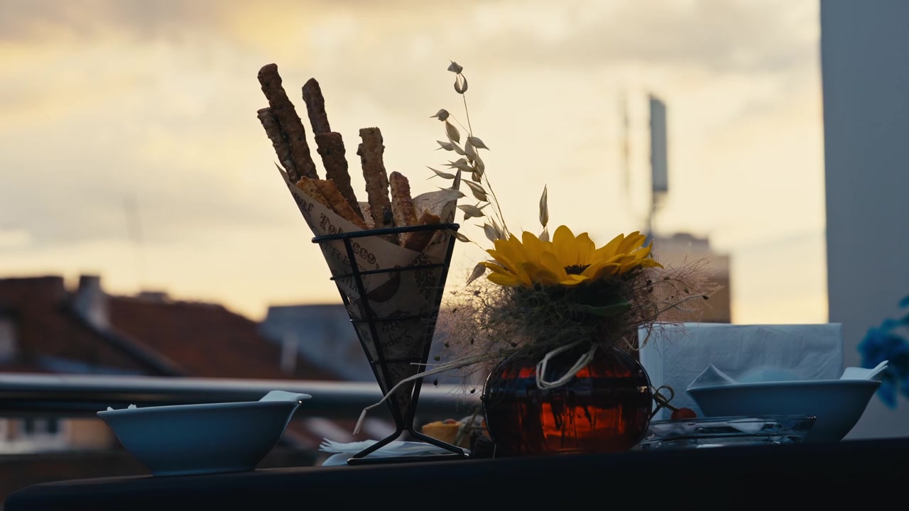 Tischarrangement auf dem Dach mit Sonnenblumen-Dekoration und Grissini-Catering bei Sonnenuntergang in der goldenen Stunde