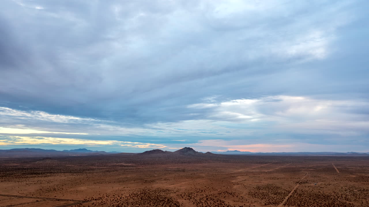Bacino e paesaggio del deserto del Mojave con le montagne in lontananza e un cielo nuvoloso sopra - hyperlapse aereo panoramico