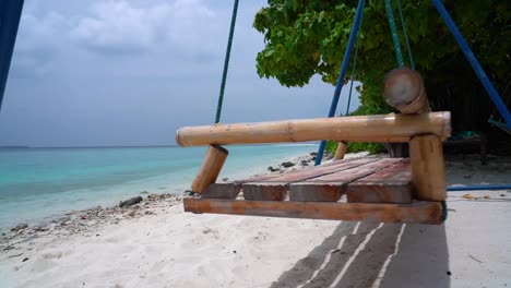 close up beautiful shot of empty swings on a paradise sandy beach facing the tranquil turquoise sea