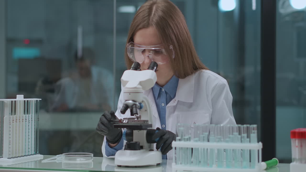laboratory technician is viewing analysis of coronavirus in lab viewing into medical microscope exploring vaccine and medicament