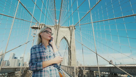 Frau-Am-Telefon-Geht-Von-Außen-Auf-Die-Brooklyn-Bridge-Mit-New-Yorker-Konzept
