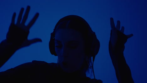 young woman wearing headphones in blue studio