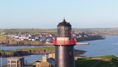 ballycotton lighthouse overlooking the fishing village in cork, ireland. - aerial shot