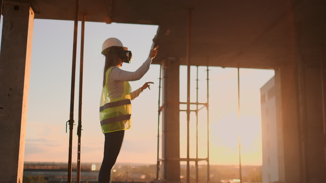 A woman engineer at a construction site in virtual reality glasses moves her hands simulating the work of the interface of the future innovative control of the construction of buildings