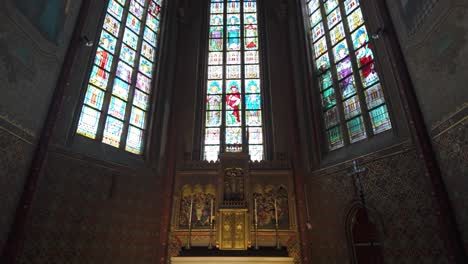 interior downward tilt of saint michael church in ghent with colorful stained glass and gothic arches to sacred altar