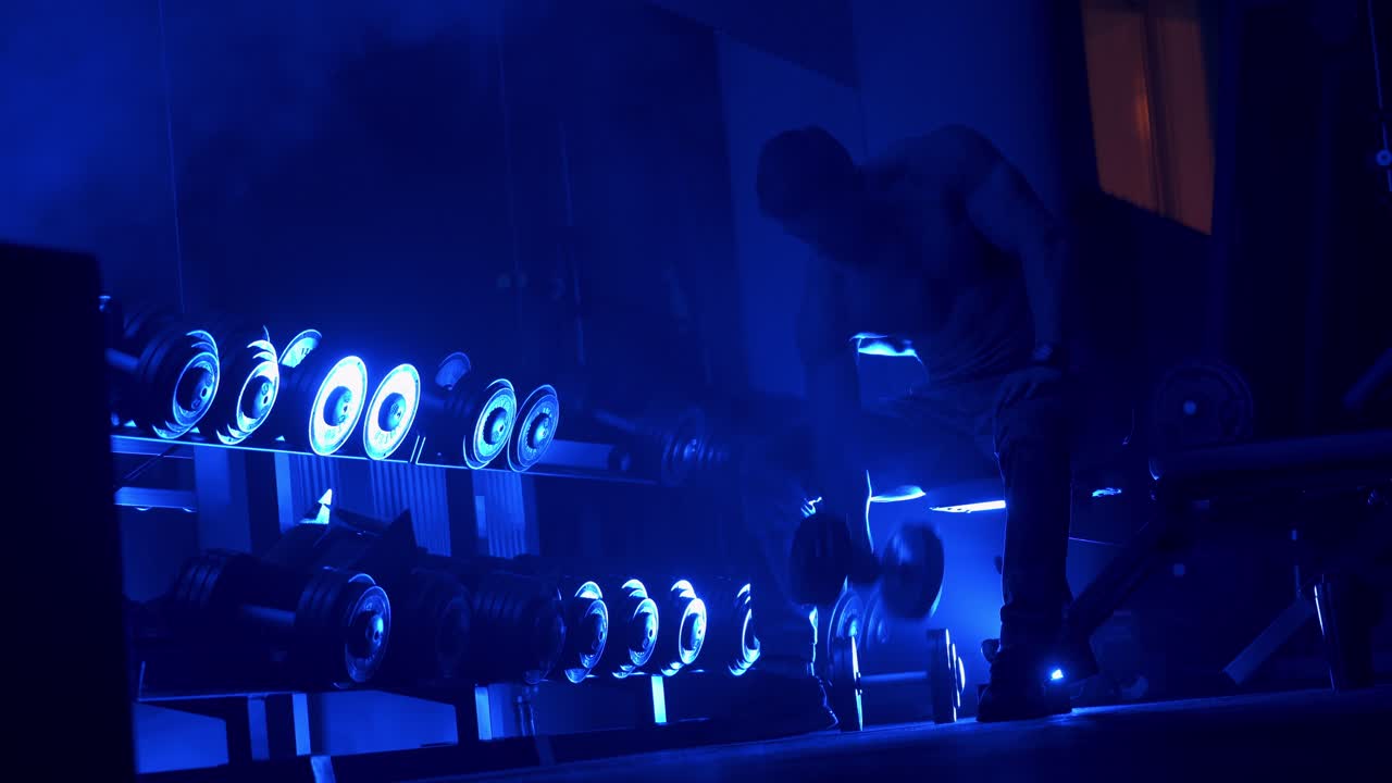 Bodybuilder in gym doing exercise. Fitness man bodybuilder with muscular torso workout with dumbbells in gym