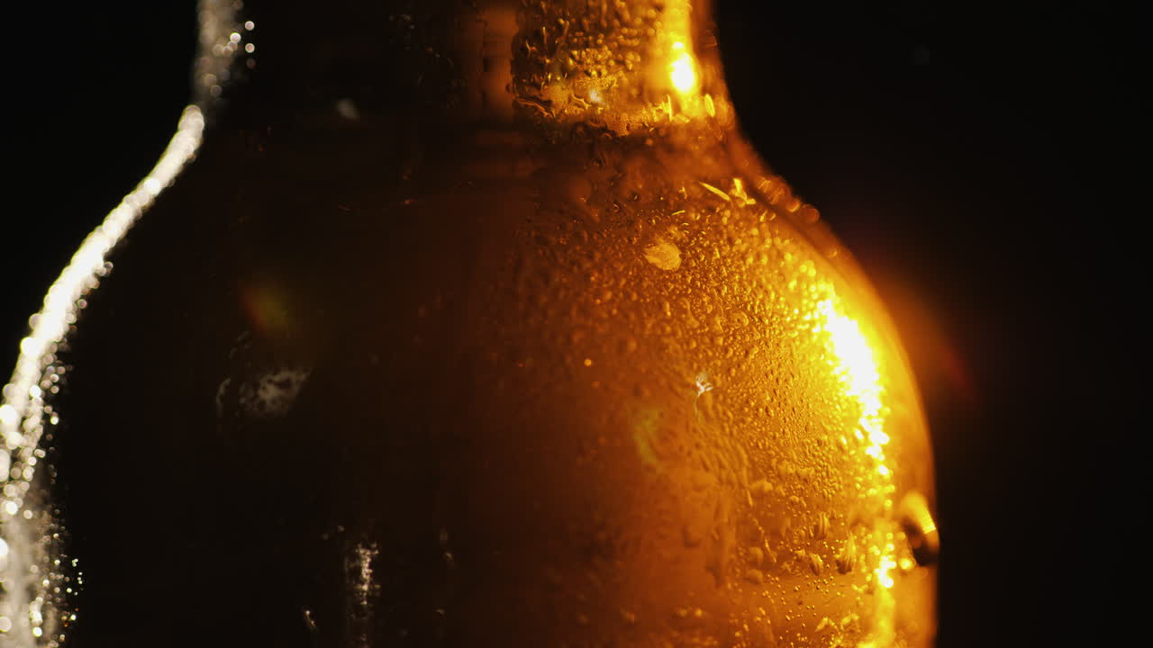 Primer plano de una botella de vidrio con gotas de agua condensada. Concepto de bebida fría sobre un fondo negro Video 4K.