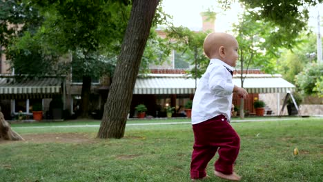 attractive little child walking by himself barefoot on green grass at park