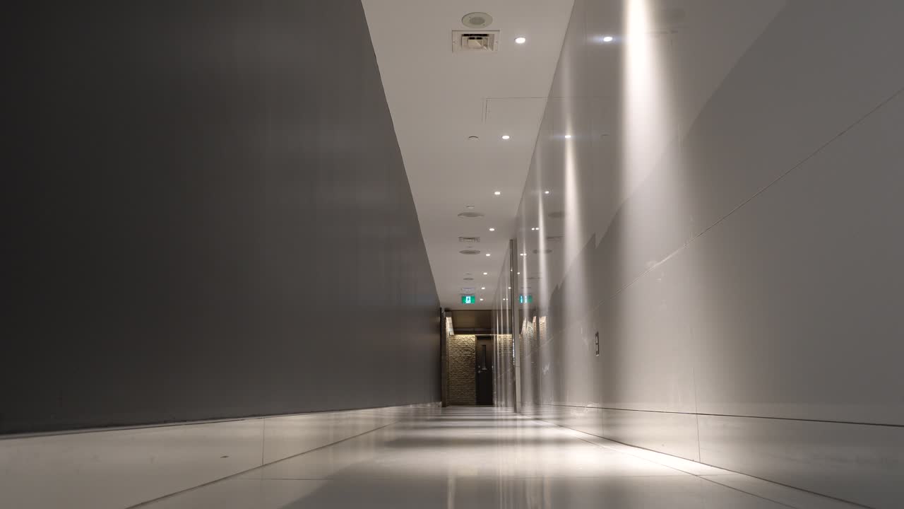 A quiet corridor where two men are walking through it. Around you can a cool perspective and the predominance of the white color.