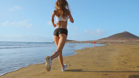 Silueta-De-Atleta-Mujer-Corriendo-En-La-Playa-Corriendo-Olas-Rompiendo-En-El-Fondo-De-La-Mañana-Junto-Al-Mar-Cámara-Lenta