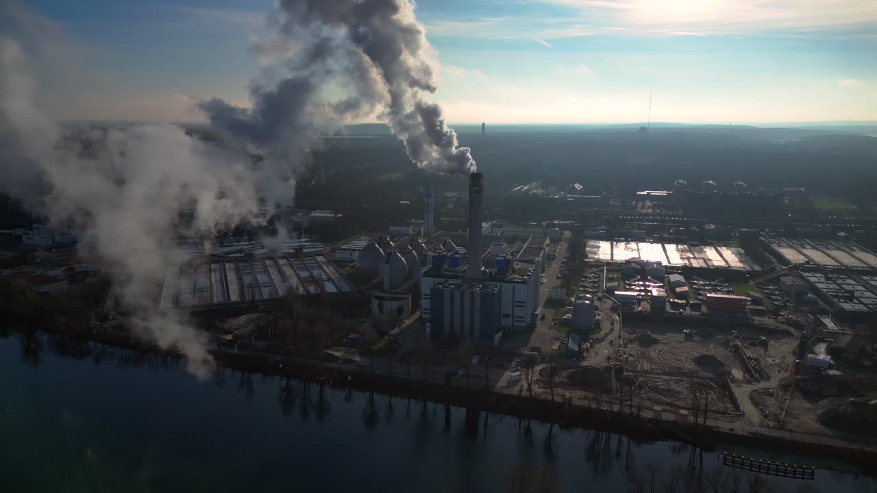 Industrial chimneys emitting white smoke over city skyline under blue sky, concept of pollution. Marvelous aerial view flight pull in drone