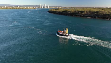 Schönes-Buntes-Fischerboot,-Das-Durch-Einen-Fluss-Mit-Einem-Schönen-Strand--Und-Anlegesteghintergrund-Kreuzt